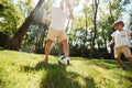 Dark-haired father and his little son dressed in the white t-shirts are playing football on a lawn on a warm day. Royalty Free Stock Photo