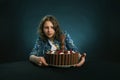 Dark-haired girl on a diet looks at a chocolate cake, struggling with the desire to eat it