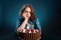 Dark-haired girl on a diet looks at a chocolate cake, struggling with the desire to eat it