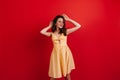 Dark-haired good-humored girl relaxed posing on red background. Woman in bright summer outfit smiling.