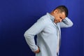 Dark-haired Latino adult man with neck, back and waist pain from trauma, injury or fracture Royalty Free Stock Photo