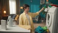 Dark-haired man sitting next to a washing machine, pouring a liquid detergent into the dispenser, planning to load the Royalty Free Stock Photo