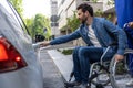 Dark-haired man on a wheelchair opening a car door Royalty Free Stock Photo