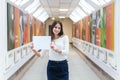 The dark-haired student girl on the campus is holding a blank sheet of paper