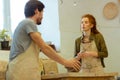 Impressed long-haired woman attentively listening to a professional pottery master