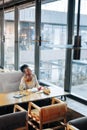 Curly dark-haired woman sitting on grey sofa in restaurant