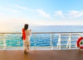 A dark haired woman on enjoys a drink on the deck of a cruise ship passing through the Greek Islands at sunset Royalty Free Stock Photo