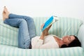 Dark haired woman lying on couch and reading a book Royalty Free Stock Photo