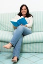 Dark haired woman lying on couch and reading a book Royalty Free Stock Photo