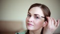 Dark-haired woman making herself up at home. Eyebrows