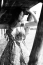 Dark-haired woman posing at the wooden pier at the lake. Woman in summer outfit with her back turned to the wooden footbridge of Royalty Free Stock Photo