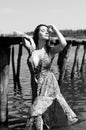 Dark-haired woman posing at the wooden pier at the lake. Woman in summer outfit with her back turned to the wooden footbridge of Royalty Free Stock Photo