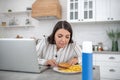 Dark-haired woman in a striped blouse looking at the plate with food Royalty Free Stock Photo