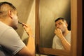 Dark-haired 40-year-old Latino man does his beauty routine, shaves with shaving cream and soap to avoid folliculitis