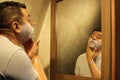 Dark-haired 40-year-old Latino man does his beauty routine, shaves with shaving cream and soap to avoid folliculitis