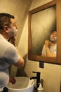 Dark-haired 40-year-old Latino man does his beauty routine, shaves with shaving cream and soap to avoid folliculitis