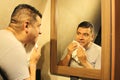 Dark-haired 40-year-old Latino man does his beauty routine, shaves with shaving cream and soap to avoid folliculitis