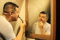 Dark-haired 40-year-old Latino man does his beauty routine, shaves with shaving cream and soap to avoid folliculitis