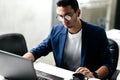 Dark-haired young architect in glasses dressed in blue checkered jacket works on the laptop in the office Royalty Free Stock Photo