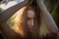 Dark-haired young woman stands with big eyes and demanding look in an old willow tree with fine shoulders Royalty Free Stock Photo