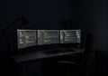 Dark home office setup with three computer monitors displaying programming code Royalty Free Stock Photo