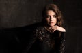 Dark horizontal portrait of a woman in a black lace dress. Professional makeup