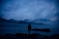 Dark human silhouette in a thick fog against the background of forest, hills and mountain river. Mysterious female figure on Royalty Free Stock Photo