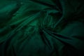 Dark image of a wet green rumpled fabric on the water, with beautiful highlights