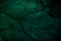 Dark image of a wet green rumpled fabric on the water, with beautiful highlights