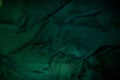 Dark image of a wet green rumpled fabric on the water, with beautiful highlights, for your creative design