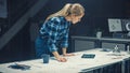 In the Dark Industrial Design Engineering Facility: Female Engineer Works with Blueprints Laying o Royalty Free Stock Photo
