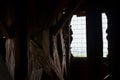 Dark interior. Wooden beams and glassless window with metallic grate.