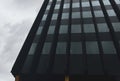 Dark key, dramatic photo of modern city, urban architecture. Black glass facade of the office building low angle view Royalty Free Stock Photo