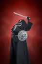 Dark knight with sword and shield over dark red background Royalty Free Stock Photo