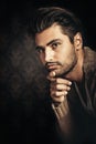 Dark light portrait of a young handsome man, hand under his chin.