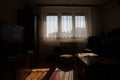 Dark living room with windows lighten by sun, back lit Interior shot of a dimly-lit back room. Sunbeams coming in dark room threw