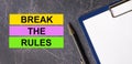 On a dark marble background, a tablet with paper, pen and three bright multi-colored strips of paper with the text BREAK THE RULES Royalty Free Stock Photo