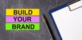 On a dark marble background, a tablet with paper, pen and three bright multi-colored strips of paper with the text BUILD YOUR Royalty Free Stock Photo