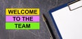 On a dark marble background, a tablet with paper, pen and three bright multi-colored strips of paper with the text WELCOME TO THE Royalty Free Stock Photo