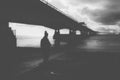 A dark mental health concept . Of a mysterious woman back to camera, under a modern bridge, With a blurred, abstract edit