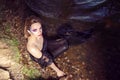 Dark Mermaid Posing Near Sea Shore on Rocks While Wearing Artistic Makeup And Facial Strassses and Black Shiny Tail Covered With