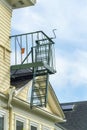 Dark metal fire escape ladder on exterior facade of beige slatted wood building in suburban area Royalty Free Stock Photo