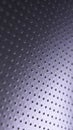 Dark metal mobile wallpaper. Perforated aluminum surface with many holes. Tinted violet or purple industrial background. Vertical