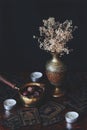 Dark, moody, esoteric, occult photo of brass decoration, vase with white flowers, hand drawn made up tarot cards spread on table