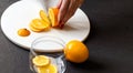 Dark moody. Food black background. On a white stone board in the hands of a girl, a knife cuts a lemon. Slices of lemon are piled Royalty Free Stock Photo