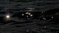 Dark moving  water surface with sparking sun reflections Royalty Free Stock Photo