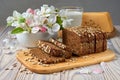 Dark multigrain bread made from rye, wheat, oats and barley with sunflower and flax seeds. Milk, cheese, apple tree flowers and Royalty Free Stock Photo