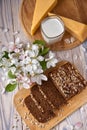 Dark multigrain bread made from rye, wheat, oats and barley with sunflower and flax seeds. Milk, cheese, apple tree flowers and Royalty Free Stock Photo