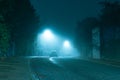 A dark mysterious eerie, English road with street lights on an atmospheric foggy winters night. UK