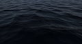 Dark and mysterious ocean surface with subtle ripples and waves creating a tranquil, deep blue texture background Royalty Free Stock Photo